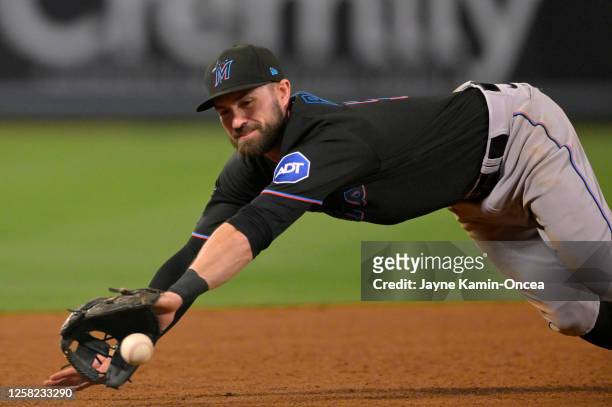 Jon Berti of the Miami Marlins dives for the ball at third base to throw out Gio Urshela of the Los Angeles Angels at first in the sixth inning at...