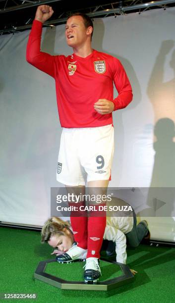 The Madame Tussauds museum employee Anna Baxter kisses the foot of a lifelike waxwork sculpture of Manchester United and England football player...