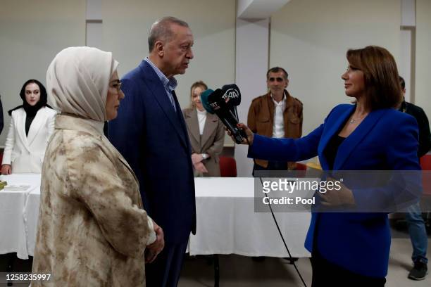 Turkish President Recep Tayyip Erdogan and his wife Emine Erdogan speak to members of the media as they arrive at a polling station to cast their...