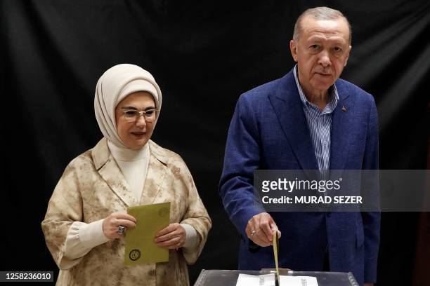 Turkey's President and presidential candidate of AK Party Recep Tayyip Erdogan , flanked by his wife Emine Erdogan , casts his ballot on the day of...