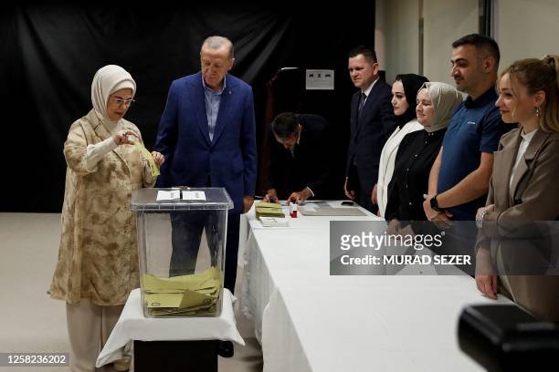 Turkey's President and presidential candidate of AK Party Recep Tayyip Erdogan looks at his wife Emine Erdogan casting her ballot on the day of the...