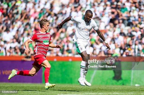 Marcus Thuram of Borussia Moenchengladbach and Robert Gumny of FC Augsburg in action during the Bundesliga match between Borussia Moenchengladbach...