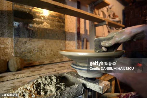 Potter makes a clay plate using a potter's wheel in a workshop in Horerzu village 16 November 2003. A potter's wheel is an ancient tool which...