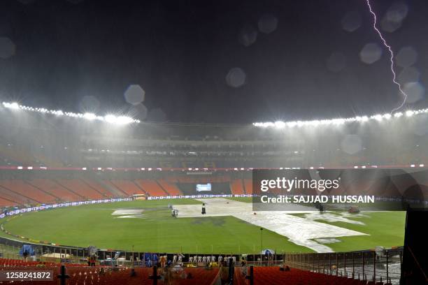 Ground staff cover the field as it rains before the start of the Indian Premier League Twenty20 final cricket match between Gujarat Titans and...