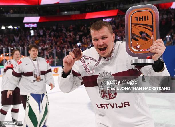 Latvia's defender Oskars Cibulskis celebrates with the bronze trophy after winning the IIHF Ice Hockey Men's World Championships third place play-off...