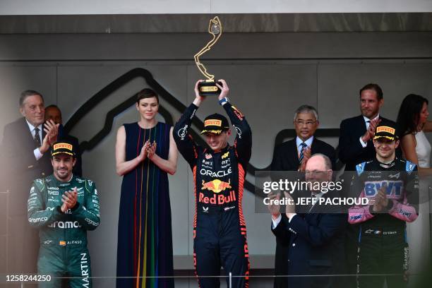 Winner Red Bull Racing's Dutch driver Max Verstappen holds up his trophy, flanked by second-placed Aston Martin's Spanish driver Fernando Alonso ,...