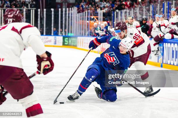 Henry Thrun of USA and Oskars Batna of Latvia battle for the ball during the 2023 IIHF Ice Hockey World Championship Finland - Latvia game between...