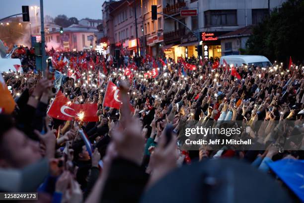 Supporters of Turkish President Recep Tayyip Erdogan hold up their mobile phones as he speaks to them from a bus top as he claims victory in the...