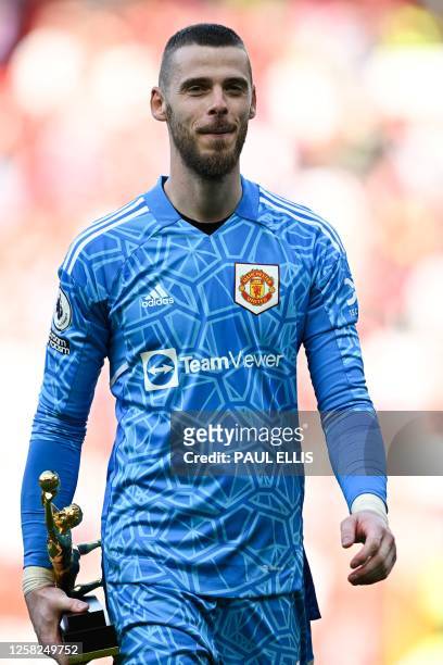 Manchester United's Spanish goalkeeper David de Gea celebrates as he holds the golden glove trophy at the end of the English Premier League football...