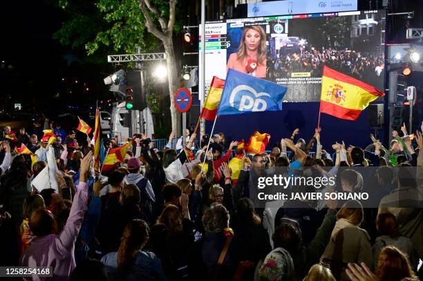 Popular Party supporters wave flags as they gather outside the party headquarters in Madrid on May 28, 2023 after the local and regional elections...