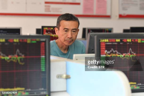 An investor looks at screens showing stock market movements at a securities company in Fuyang in China's eastern Anhui province on May 29, 2023. /...