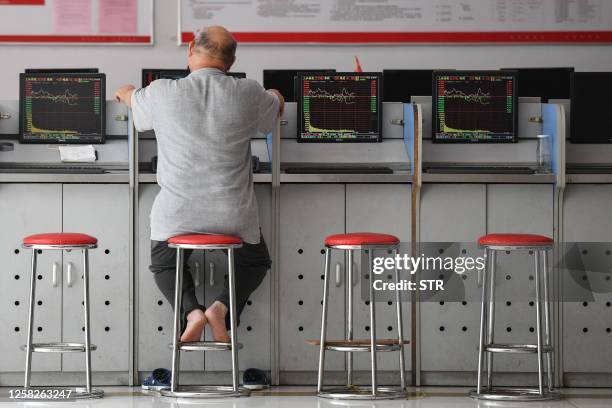 An investor looks at screens showing stock market movements at a securities company in Fuyang in China's eastern Anhui province on May 29, 2023. /...