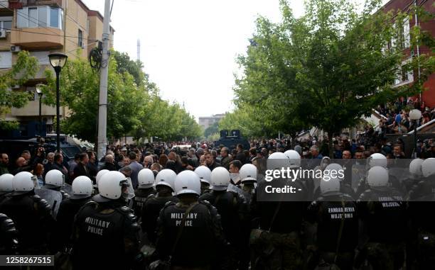 Kosovo riot police along with KFOR military police, secure access to a municipal building in Zvecan as Kosovo Serbs gather outside the building after...