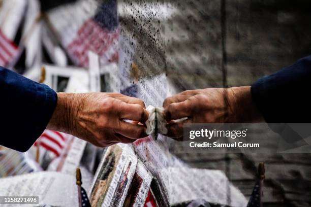 David Loesch, a 101st Airborne Veteran of the Vietnam War, wipes rainwater from the name of a soldier from his unit amongst the names engraved on the...