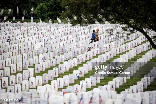 Visitors walk through the rolling hills of headstones marking the final resting place of service men and women in Arlington National Cemetery on...