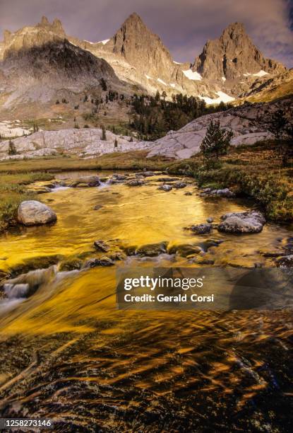 sonnenaufgang mit wolken über der minaret range der sierra navada mountains und einem kleinen bach, der den vordergrund hinunterfließt. ansel adams wilderness area, kalifornien. - wildnisgebiet ansel adams stock-fotos und bilder