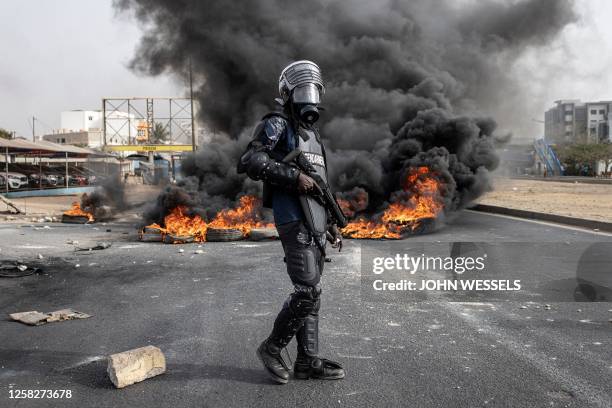 Senegalese gendarme stand near a smoke billowing from burning tyres during a protest in Dakar on May 29 over the arrest of opposition leader Ousmane...