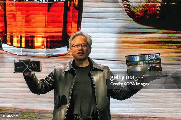 Nvidia president and CEO Jensen Huang holds a graphics card NVIDIA 4060Ti and a laptop at a keynote presentation at COMPUTEX. The COMPUTEX 2023 runs...