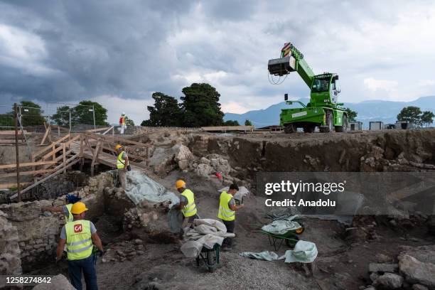 Maintenance workers cover the main finds with tarpaulins to shelter them from the rain after the press preview of the new excavation area of Regio XI...