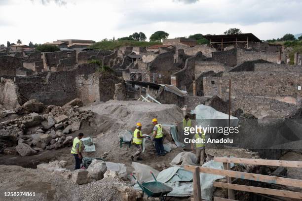 Maintenance workers cover the main finds with tarpaulins to shelter them from the rain after the press preview of the new excavation area of Regio XI...