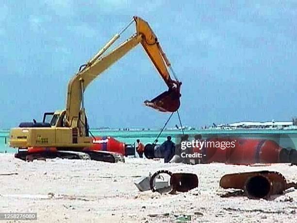 Back-hoe lifts pipes 23 August on this reclaimed island in the Indian Ocean atoll nation of the Maldives to carry out faster dredging work to expand...