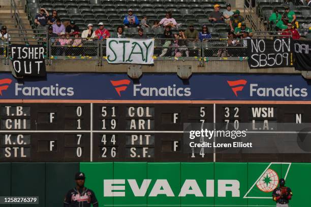 Fans sit behind signs referencing plans for the Oakland Athletics to move to Las Vegas during a game against the Atlanta Braves at RingCentral...