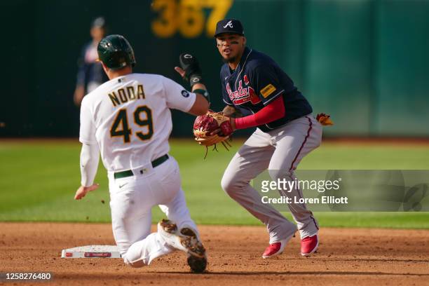 Orlando Arcia of the Atlanta Braves turns a double play over Ryan Noda of the Oakland Athletics at second base in the third inning at RingCentral...