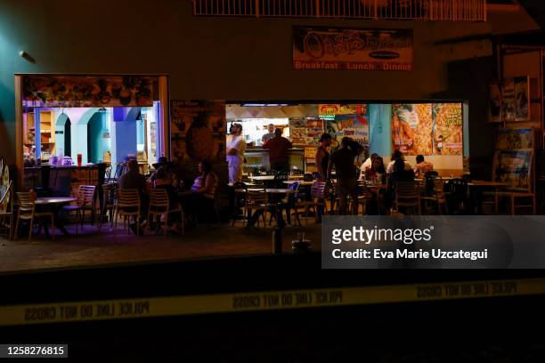 People are seen at a bar next to a crime scene as law enforcement officers respond to a shooting at Hollywood Beach on May 29, 2023 in Hollywood,...