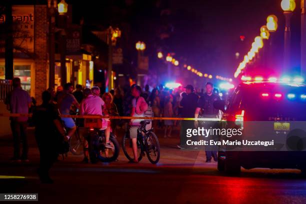 Beachgoers are seen next to law enforcement officers on a crime scene as they respond to a shooting at Hollywood Beach on May 29, 2023 in Hollywood,...
