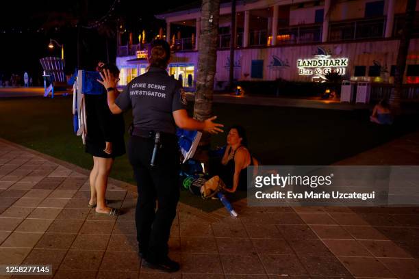 Law enforcement officers talk to beachgoers next to a crime scene as they respond to a shooting at Hollywood Beach on May 29, 2023 in Hollywood,...