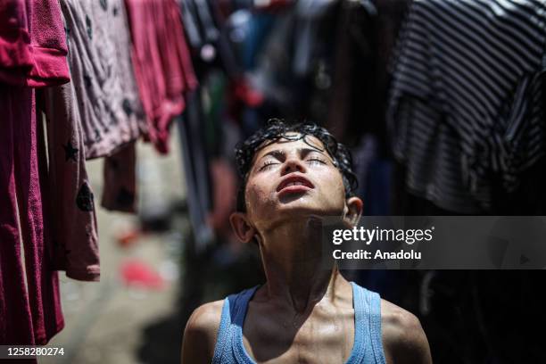 Palestinian boy tries to cool off himself during hot weather under difficult conditions in Al-Zaytun district of Gaza City, Gaza on May 29, 2023. Due...