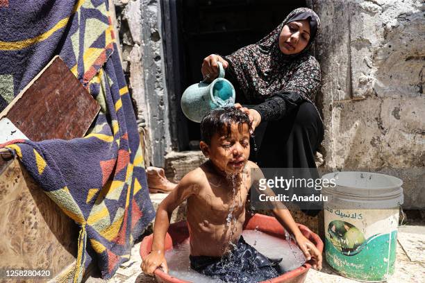 Palestinian woman gives a her child a bath under difficult conditions in Al-Zaytun district of Gaza City, Gaza on May 29, 2023. Due to ongoing...