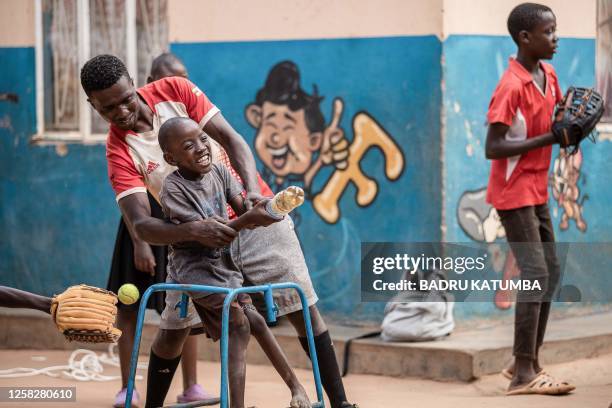 Ugandan baseball player Dennis Kasumba who dreams of becoming Uganda's first US Major League Baseball player plays with a child at St. Lilian Jubilee...