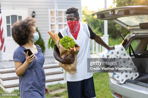 jeune couple afro inquiet déchargeant des sacs d’épicerie et du papier toilette après être arrivé du magasinage au moment de la pandémie de virus - buying toilet paper photos et images de collection