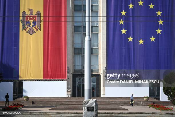 Local resident walks past the European and Moldovan flags displayed on the Moldovan Government building in Chisinau on May 29, 2023. On June 1, 2023...