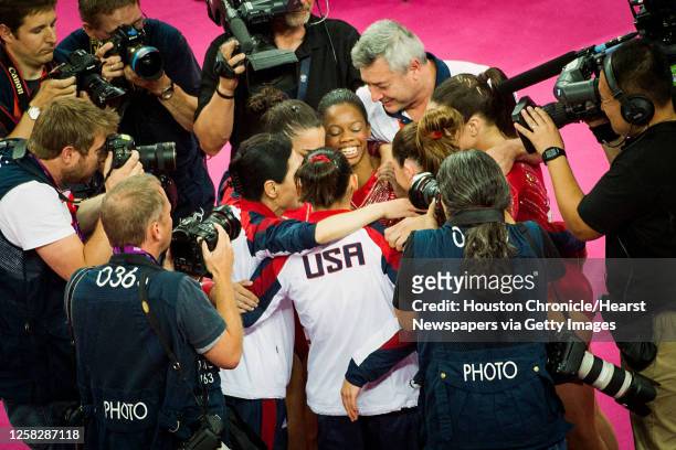 Gabby Douglas, facing, celebrates with teammates as photographers crowd around the U.S. The after their scores on their final apparatus gave them the...