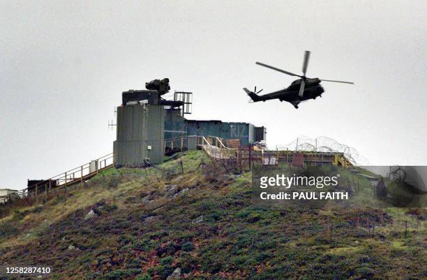 British Army helicopter hovers over the Romeo 101 observation post near Camlough in South Armagh 25 October 2001 as army engineers begin dismantling...