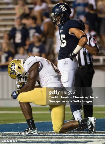 Bruins running back Johnathan Franklin kneels in prayer after scoring on a 22-yard touchdown run during the second half as Rice Owls cornerback...