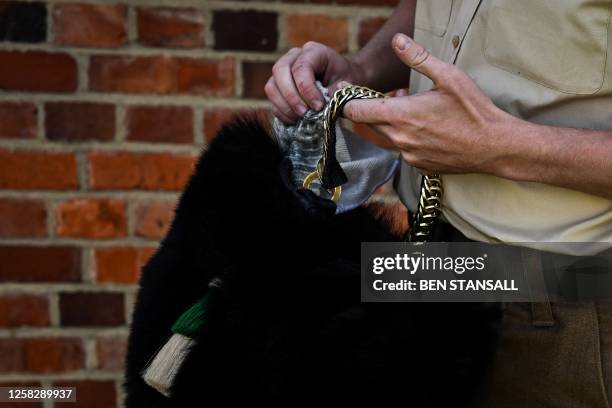 Welsh Guardsman from the Guards Division polishes the chin chain of his bearskin hat as he prepares to take part in a parade rehearsal at Pirbright...