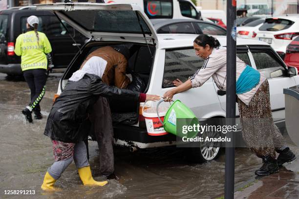 People with buckets at Sihhiye Yeni Sehir Bazaar after a heavy rainfall in Ankara, Turkiye on May 30, 2023.
