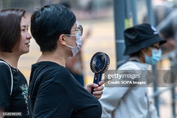 Woman uses a USB fan to cool herself in Quarry Bay as an amber alert for extreme heat is issued. The Hong Kong Observatory recently launched a new...