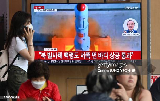 People watch a television screen showing a news broadcast with file footage of North Korea's rocket launch, at the Seoul Railway Station in Seoul on...