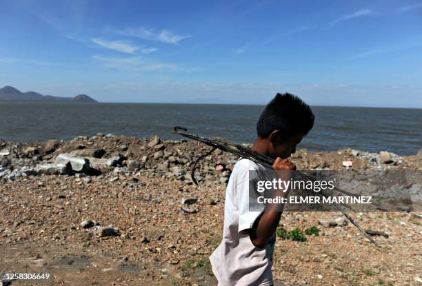 Youngster carries iron rods extracted from concrete blocks left after 1972 earthquake on the shore of the Xolotlan Lake, north of Managua, on March...