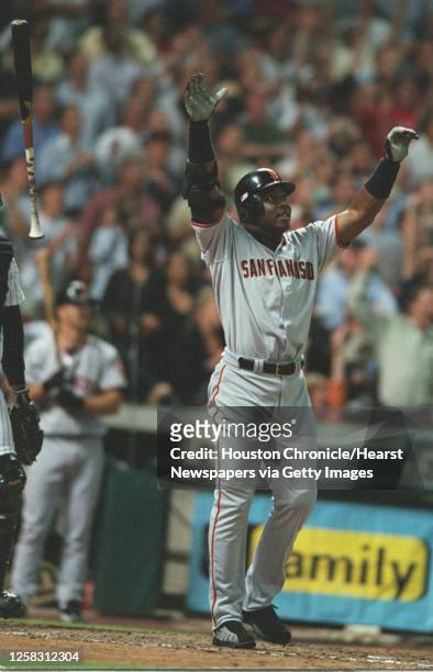 Barry Bonds of the San Francisco Giants raises his arms and tosses his bat as he watches his 70th home of the season -- hit off Houston Astros...