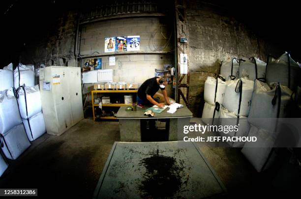 An employee works near bags containing material from electric cables, 02 August 2006 at the MTB Recycling company in Trept. Un employé travaille à...