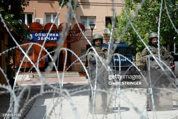 Led Kosovo Force soldiers, wearing full riot gear, stand behind a barbed wire perimeter around the municipal building in Zvecan, northern Kosovo,...