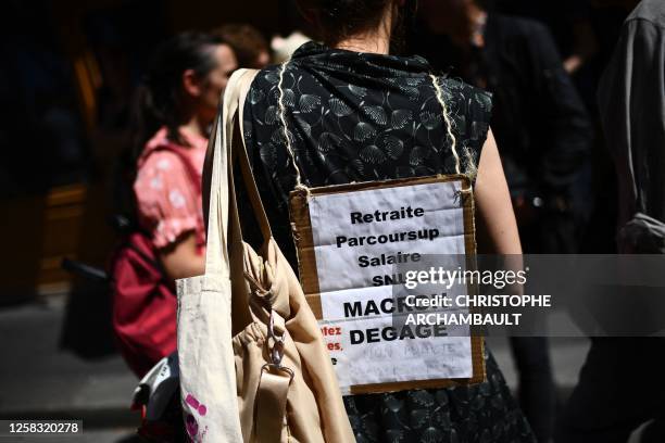 Protester wears a placard that reads "Retirement, Career, Salary, SNU, Get lost, Macron" as she takes part in a demonstration against the...