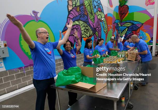 Chevron employees Luc Huyse, left, and Janell Long, take a moment to dance along to "YMCA" as they helped to package up food items for the Backpack...