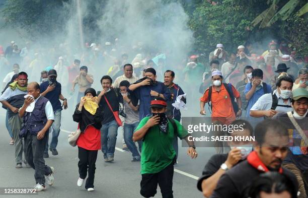 Demonstrators run away as Malaysian anti-riot police fire tear gas shells near Merdeka Square in Kuala Lumpur on August 01, 2009. Malaysian police...