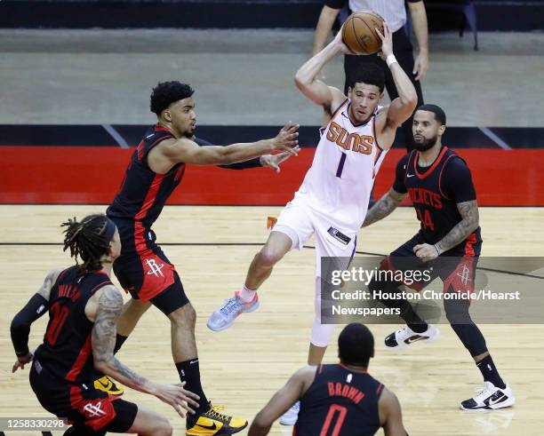 Phoenix Suns guard Devin Booker passes the ball against Houston Rockets forwards Kenyon Martin Jr. And D.J. Wilson during the third quarter of an NBA...